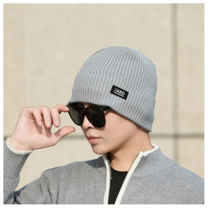 Close-up of light grey ribbed knit beanie with a woven brand tag for outdoor warmth