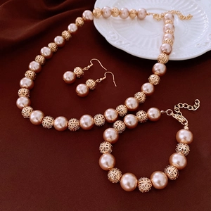 Detail of pink pearl and golden hollow sphere jewelry set including necklace and bracelet
