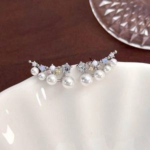 Macro shot of zircon flower butterfly earrings with pearls on a white ceramic plate