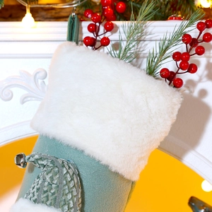 Close-up of Morandi green Christmas stocking with white faux fur and pine needles