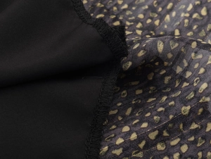 Detail view of stitching between black opaque fabric and gold polka dot sheer material