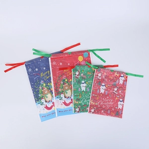 Detail view of assorted Christmas drawstring gift bags with cartoon patterns and festive ribbons