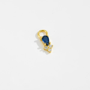 Detail of gold pear-shaped blue gemstone pendant with small white stones on white backdrop