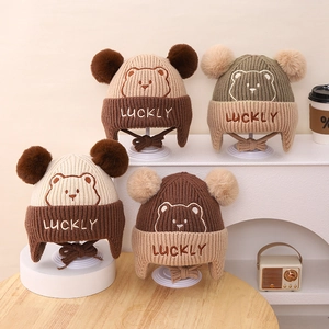 Detail showing knit texture and LUCKY bear embroidery on infant warm earflap hats