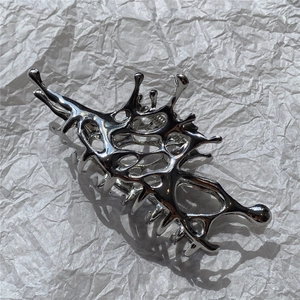 Macro detail of silver liquid metal hair claw clip with irregular 3D butterfly hollow design