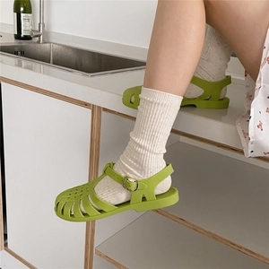 Close-up of bright green jelly woven sandals with silver buckle and white socks
