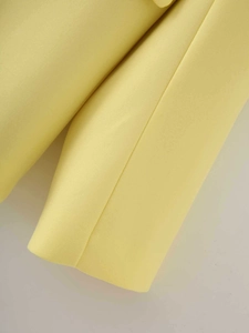 Close-up of pale yellow satin blazer showing twill fabric texture and stitching detail