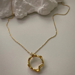 Close-up of gold 925 sterling silver necklace with irregular wave-shaped pendant