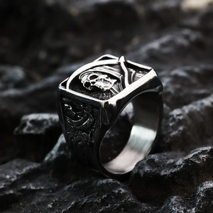 Macro shot of stainless steel skull ring with gothic relief details on black rock