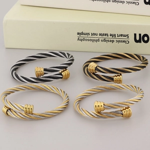 Twisted cable stainless steel cuff bracelets in gold and silver finish on book