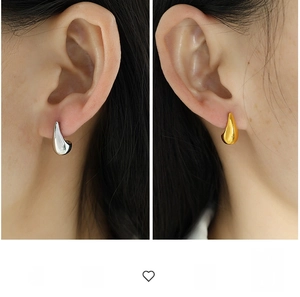 Close-up of minimalist gold and silver teardrop earrings on ears with metallic finish