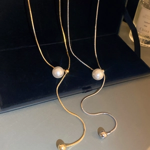 Minimalist gold and silver Y-shaped pearl necklaces displayed on elegant velvet box