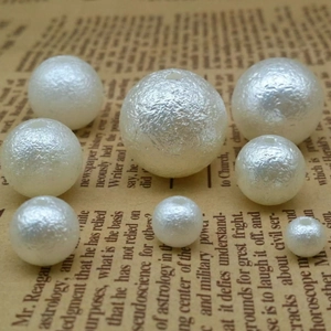 Macro shot of white wrinkled texture faux pearls with holes on vintage newspaper background