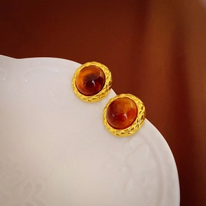 Close-up of vintage resin earrings with gold matelasse texture on a white porcelain dish