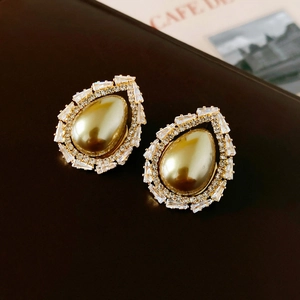 Vue rapprochée de boucles d'oreilles perles vintage avec halo de zircons cubiques