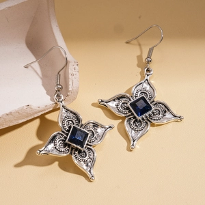 Dettaglio di orecchini a fiore in argento vintage con cristalli blu quadrati