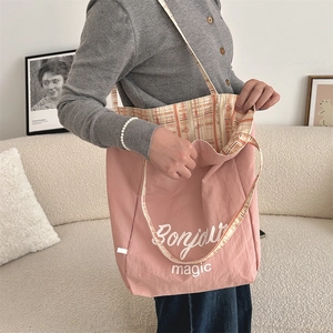 Detailed view of pink canvas tote bag showing Bonjour magic print and plaid lining