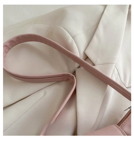 Detail of soft matte leather strap and handle on a minimalist pink underarm bag