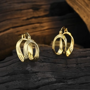 Detailansicht der dreilagigen goldenen geometrischen Creolen mit polierter Oberfläche