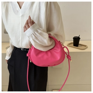 Close-up of a pink crescent bag featuring a knotted handle and sleek vegan leather texture