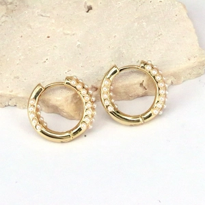 Macro shot of gold hoop earrings adorned with triple rows of elegant white pearls