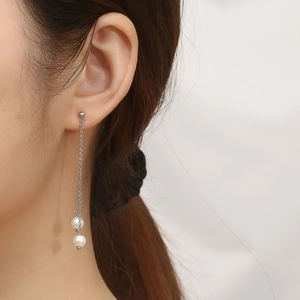 Detail shot of elegant silver tassel earrings with white pearls on a female model