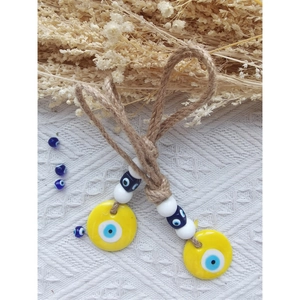 Close-up of handmade yellow evil eye wall hangings with hemp rope and blue glass beads