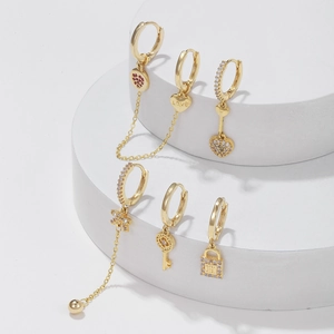 6-piece gold heart and key zircon charm earrings set on a minimalist white pedestal
