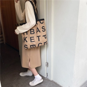 Close-up of khaki canvas tote bag featuring large black letter print and black handles