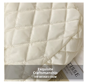 Close-up of quilted rhombic stitching and soft white fabric on a large puffer handbag