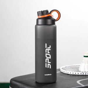 Close-up of matte dark gray sports water bottle with orange handle and badminton racket
