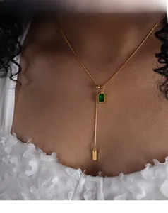 Detail of Y-shaped gold necklace with emerald-cut green gemstone and BABY tag