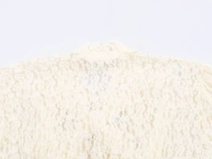 Detailed macro view of cream lace fabric texture and floral jacquard pattern on a jumpsuit