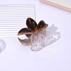 Detail shot of a 8cm clear gradient brown plumeria hair claw clip on a white surface