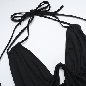 Detail of cowl neck halter jumpsuit featuring drawstrings and gathered black fabric