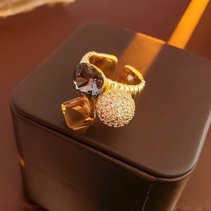 Detailed macro of gold-plated open ring featuring amber and smoky grey cubic zirconia