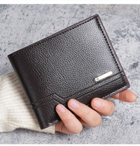 Detail of dark brown lychee grain leather wallet with golden metal accent and blue stone