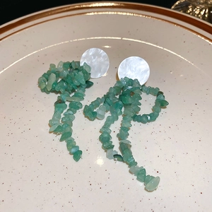 Detailed view of long tassel earrings with white shell studs and green stone beads