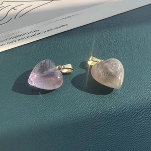Macro shot of heart-shaped amethyst and smoky quartz pendants with gold clasp on leather