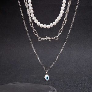 Close-up of triple-layered necklace featuring pearls and blue evil eye pendant