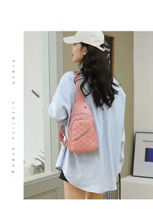 Pink quilted crossbody chest bag with gold zipper shown on model in a casual indoor setting