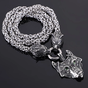 Detailed close-up of a silver Viking wolf pendant with green gemstones and braided chain