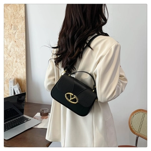 Detail of the elegant black leather handbag with lizard pattern and golden V-shaped buckle