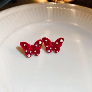 Détail macro de boucles d'oreilles papillon en velours rouge et perles blanches