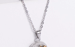 Macro du fermoir de collier en acier titane argenté et du bord du pendentif texturé