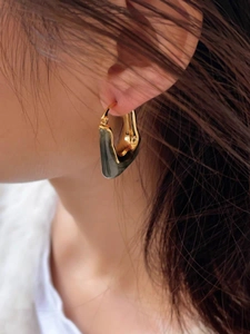 Detailed close-up of 18K gold-plated U-shaped earrings with dark amber resin inlay