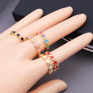 Detailed view of colorful enamel star rings in 18K gold plated copper on a hand model