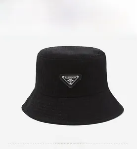 Detailed view of black bucket hat featuring crinkled fabric and a metal triangle logo