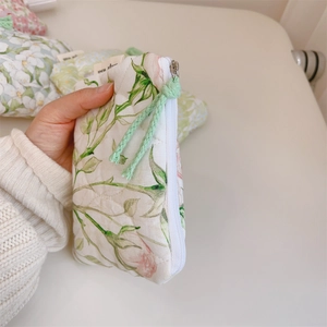 Detailed close-up of small quilted cotton floral pouch held in hand for size comparison