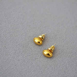 Macro shot of minimalist gold oval bean stud earrings with polished mirror finish